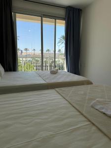 two beds in a bedroom with a large window at إقامة فندقية بخصوصية كاملة في مراسي in El Alamein