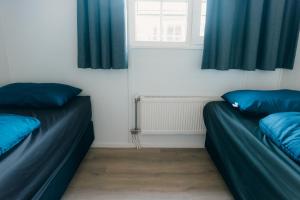 two beds in a room with blue curtains at Bungalow Bunckman Luxury 10 persons in Voorthuizen +15 photos