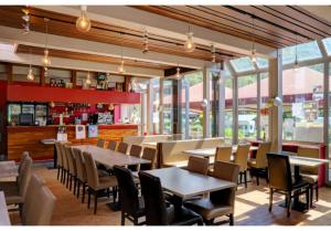 een restaurant met tafels, stoelen en ramen bij Coco Sweet with sanitary in La-Roche-en-Ardenne