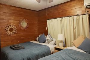 two beds in a room with wood paneling at パイナガマビーチハウス in Miyako-jima