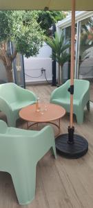 un patio con tavoli, sedie e un ombrellone di Villa cosy à 200 m de la mer a Cap d'Agde