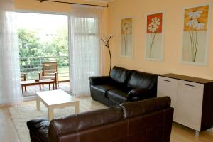 a living room with a leather couch and a balcony at Dunalux Apartman in Győr