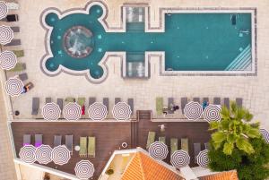 una vista sulla piscina con orologio di King Jason Paphos - Designed for Adults by Louis Hotels a Paphos