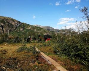 a red house on a hill with a mountain at Reinunga Eco Hytta - Mountain lodge near Myrdal accessible only by train or bike in Myrdal