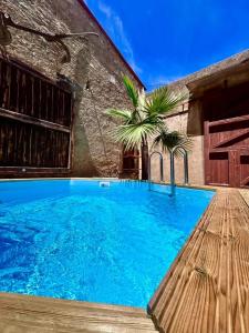 a large blue swimming pool next to a building at La Maison Coloniale Suites privatives de luxe in Torreilles