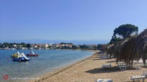 a beach with boats in the water and chairs at Apartman Lunna in Vrsi