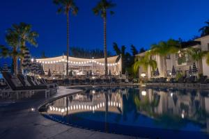 a resort pool with chairs and palm trees at night at King Jason Paphos - Designed for Adults by Louis Hotels in Paphos