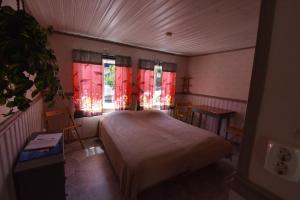 a bedroom with a bed and windows with red curtains at Bo bra i Borgholm in Borgholm