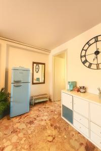 a kitchen with a refrigerator and a clock on the wall at Casa vacanza 'Note di mare' in Torvaianica