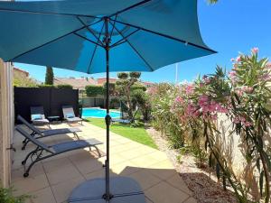 a blue umbrella on a patio with chairs and a pool at Villa 3 étoiles avec piscine privée, 500m de la plage, 4 chambres pour 6-8 pers. au Grau-du-Roi - FR-1-307-157 in Le Grau-du-Roi