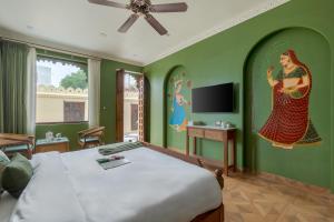 una camera da letto con pareti verdi con un letto e una TV di SaffronStays Rang Havelii - Superior room in heritage haveli near City Palace with rooftop chhatri & pool in Udaipur a Udaipur