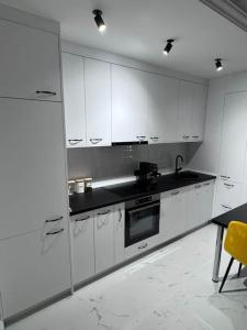 a white kitchen with white cabinets and a table at Apartman Andrija in Igalo +5 photos
