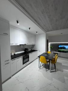 a kitchen with white cabinets and a table and yellow chairs at Apartman Andrija in Igalo