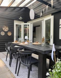 a dining area with a large black table and chairs at Dromen op 1 - Stijlvol boshuis op de Veluwe met veranda en grote omheinde tuin! in Nunspeet