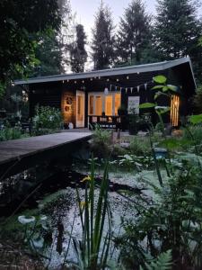 a house with a pond in front of it at Dromen op 1 - Stijlvol boshuis op de Veluwe met veranda en grote omheinde tuin! in Nunspeet