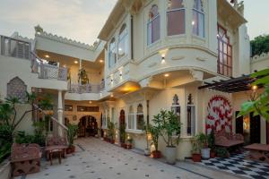 un grande edificio con cortile con piante in vaso di SaffronStays Rang Havelii - Superior room in heritage haveli near City Palace with rooftop chhatri & pool in Udaipur a Udaipur