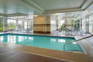 a swimming pool in a building with chairs and tables at Residence Inn by Marriott Ottawa Airport in Ottawa
