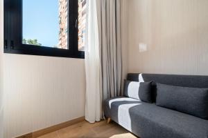 Una sala de estar con un sofá y una ventana. en Dobo Madrid Betanzos, en Madrid