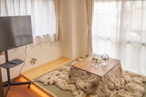 a living room with a table and a tv at Direct to Shinjuku Two bedrooms Higashi-Nakano Station Free luggage storage in Wada