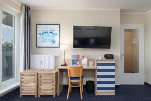 a hotel room with a desk and a tv on the wall at Seestern - Charmante 2-Zimmer-Wohnung mit Balkon in Zingst