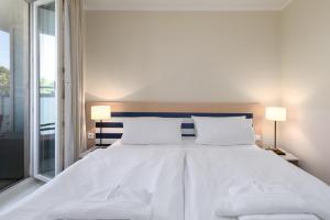 a bedroom with a large white bed with two lamps at Seestern - Charmante 2-Zimmer-Wohnung mit Balkon in Zingst