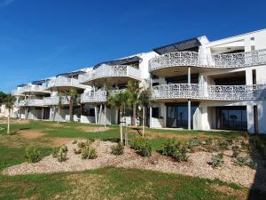 an apartment building with white balconies and palm trees at Appartement en bord de mer, 2 chambres, piscine, parking, animaux admis - FR-1-194-231 in La Tranche-sur-Mer