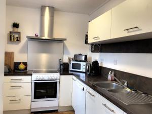 a kitchen with white cabinets and a sink and a microwave at Maison 3* proche plage, forêt et pistes cyclables avec jardin, barbecue et WIFI - FR-1-652-12 in Saint-Jean-de-Monts +11 photos