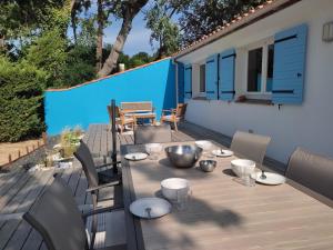 a wooden table with plates and bowls on a deck at Maison 3* proche plage, forêt et pistes cyclables avec jardin, barbecue et WIFI - FR-1-652-12 in Saint-Jean-de-Monts