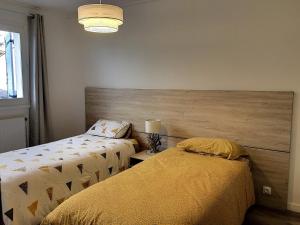 a bedroom with two beds and a wooden headboard at Maison 3* proche plage, forêt et pistes cyclables avec jardin, barbecue et WIFI - FR-1-652-12 in Saint-Jean-de-Monts