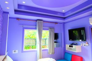 Cette chambre violette dispose d'une fenêtre et d'un canapé bleu. dans l'établissement Rak Kun Resort 2, à Nakhon Sawan