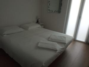 a white bed in a room with two towels on it at Casa sulla Piazzetta in Saluzzo