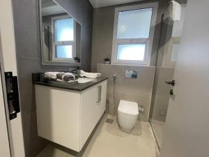 Un baño con inodoro, lavabo y espejo. en غرفة نوم بالشارقة, en Sabkhah