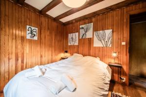 a bedroom with a white bed in a wooden wall at Chalet Chez Juju in Abondance