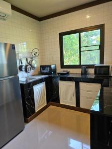 a kitchen with black counter tops and a window at Bang Po Hut in Ban Bang Po