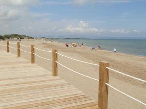 a wooden boardwalk on a beach with people on it at Vacaciones ideales: apto con piscina, cerca del mar, wifi, aire opcional, admite mascotas, playa perros - ES-184-11 in Riumar