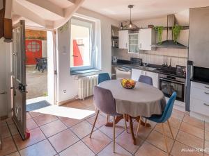 a kitchen with a table and some chairs and a table and a kitchen at Charmante maison 1930 centre Hennebont, déco actuelle, terrasse, jardin clos, 2 chambres, wifi inclus - FR-1-349-204 in Hennebont