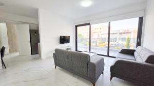a living room with two couches and a large window at Poolside Lux Apartment in Larnaca