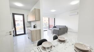 a white living room with a table and a kitchen at Poolside Lux Apartment in Larnaca