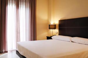 Un dormitorio con una gran cama blanca y una ventana. en Hotel Real Balneario Carlos III, en Trillo