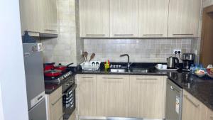 a kitchen with white cabinets and a black counter top at Yas Amazon - Stylish 1BR Apartment on Yas Island, Near Yas Mall in Abu Dhabi