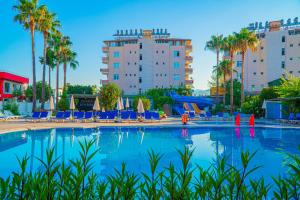 a large swimming pool with blue chairs and palm trees at Bahama Beach Konaklı in Konaklı
