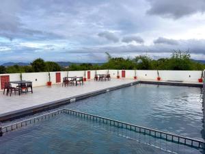a swimming pool with tables and chairs on a patio at Leopard Hill Resort - Bandipur in Bandipūr