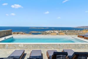 a pool with chairs and the ocean in the background at "Aloe On the Rock" by Explore Andros in Batsi