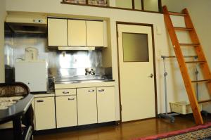 una cocina con armarios blancos y una escalera. en Petit Hotel Koizumi, en Lago Toya