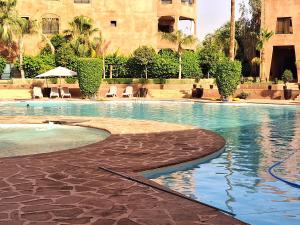 a swimming pool with chairs and a building at L'ECRIN de la PALMERAIE in Dar Caïd Layadi
