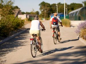 two people riding bikes down a road at Chalet Confort 2 Chambres avec Piscine Chauffée et Climatisation en Bretagne Sud - FR-1-783-19 in Marzan