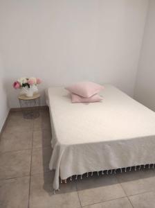 a white bed with pink pillows and a table with flowers at Villa Entre Terre & Mer in Vidauban