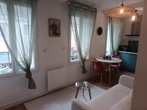 sala de estar con sofá, mesa y ventanas en Résidence La Marée Verte 1 Studio - 1 Duplex, en Saint-Valéry-en-Caux