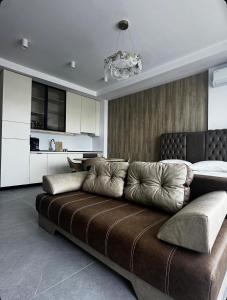 a living room with a brown couch and a kitchen at Axxis Luxury Studio in Mamaia