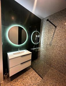 a bathroom with a sink and a mirror and a shower at Axxis Luxury Studio in Mamaia